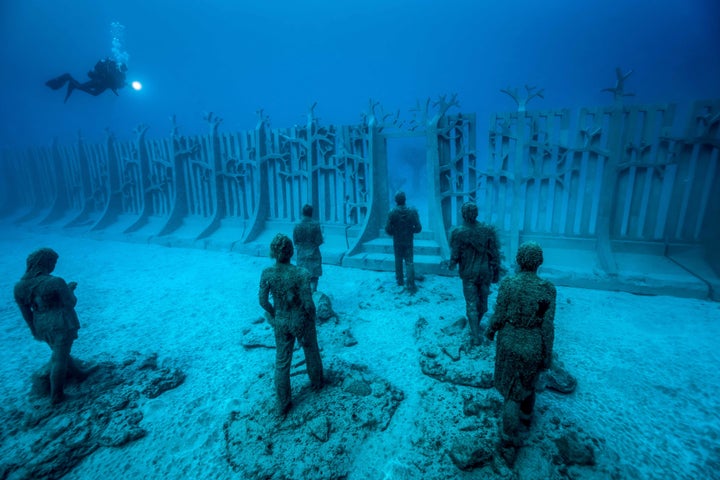 A diver studies "Crossing the Rubicon," a giant underwater wall installation. 