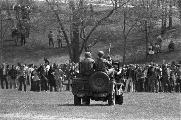 Masked National Guardsmen fire a barrage of tear gas into a crowd of demonstrators on the campus of Kent State University in