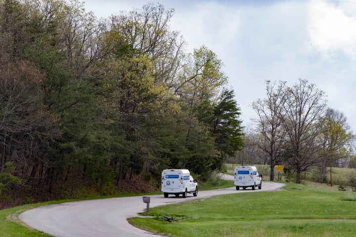 Crime scene investigation vehicles drive up Union Hill Road after bodies of eight family members were found that day at four