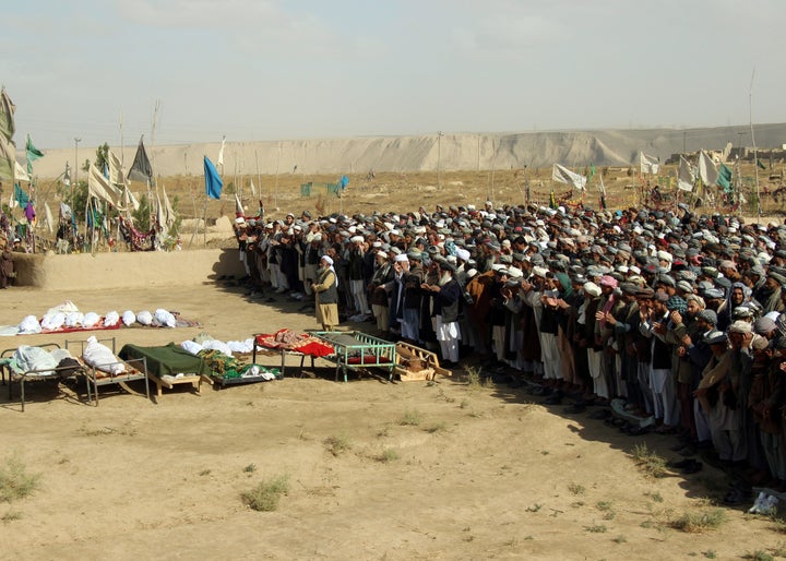 Afghans perform prayers at the funeral for the victims killed by an airstrike called in to protect Afghan and U.S. forces dur