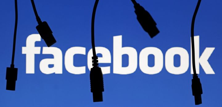 Electronic cables are silhouetted next to the logo of Facebook in this September 23, 2014 illustration photo. Parts of the popular social media site appeared to go offline Friday.