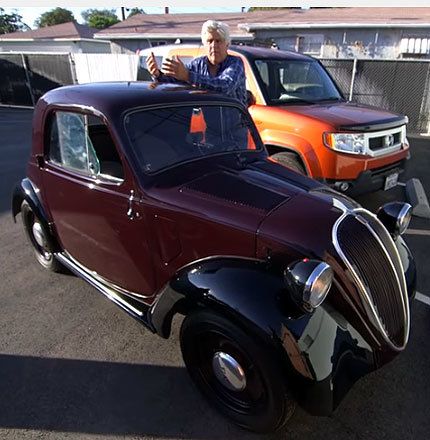 Jay Leno poses with his “Topolino,” a Fiat 500 from the 1940s.