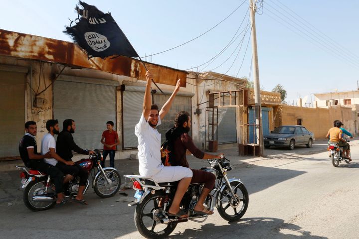 A resident of Tabqa city touring the streets on a motorcycle waves an Islamist flag in celebration after Islamic State militants took over Tabqa air base, in nearby Raqqa city Aug. 24, 2014.