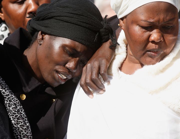 Akon Guode collapses against at friend during the funeral for her three children in 2015.