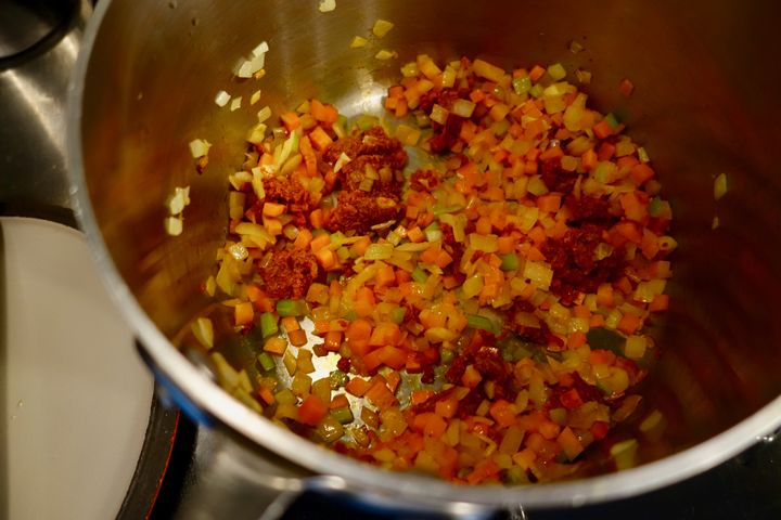 Adding ’nduja to aromatic vegetables in the bean pot