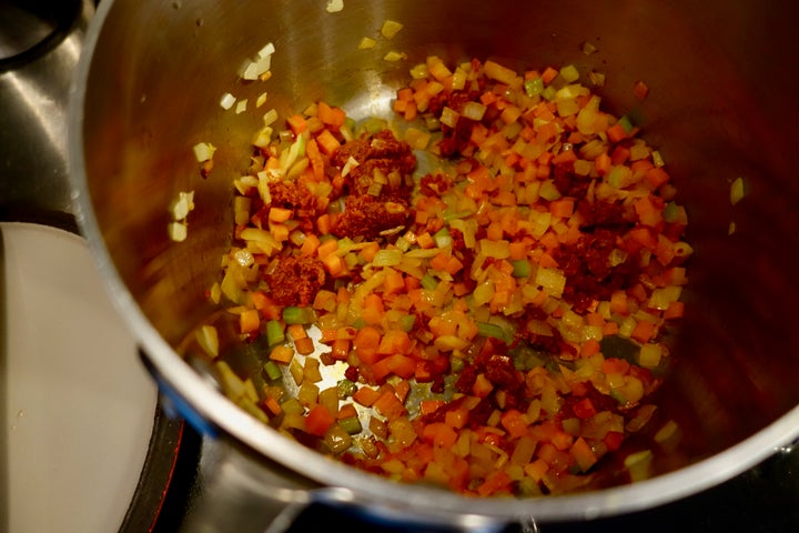 <p>Adding ’nduja to aromatic vegetables in the bean pot</p>