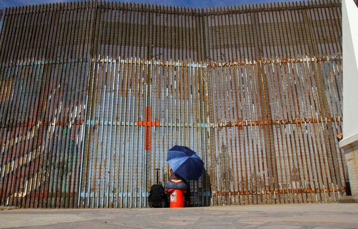 A woman talks to her relatives across a fence separating Mexico and the United States, in Tijuana, Mexico, November 12, 2016. REUTERS/Jorge Duenes