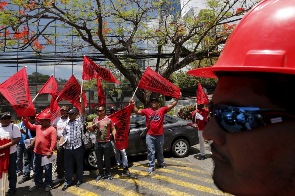 Members of the National Union of Workers of Construction and Similar Industries (SUNTRACS) hold up their flags outside Mossac