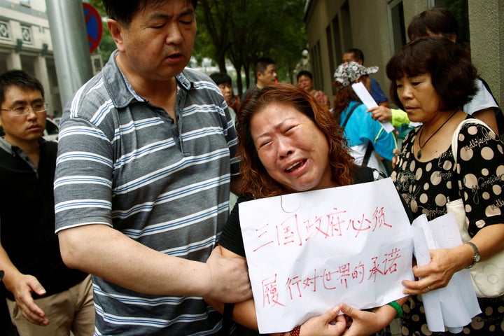 A relative of one of the missing passengers holds a sign that reads: "The three governments have an obligation to the world to carry out their promise." 