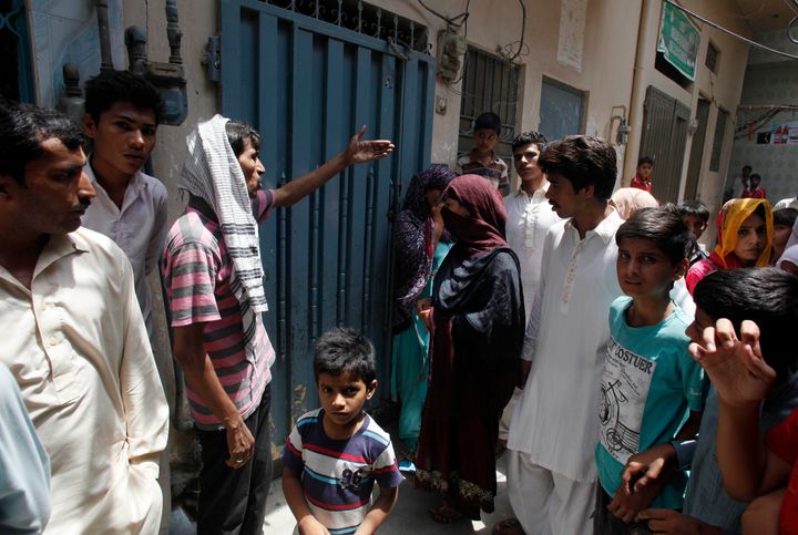 Local residents gather outside the home of Parveen Rafiq, who burned her daughter alive, after the incident in Lahore, Pakistan