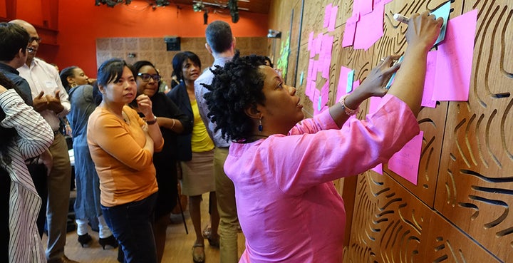Melinda Weekes-Laidlow, a racial equity trainer with Race Forward, arranges sticky notes on a wall as she leads cultural advocates in a “gallery walk” exercise.