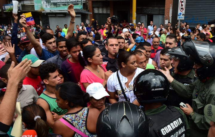 People argue with members of Venezuela's National Guard as they try to line up in front of a supermarket in Caracas on June 2, 2016.