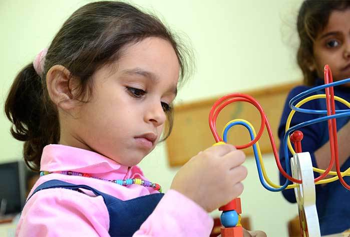 Palestinian preschooler exploring her new learning toy