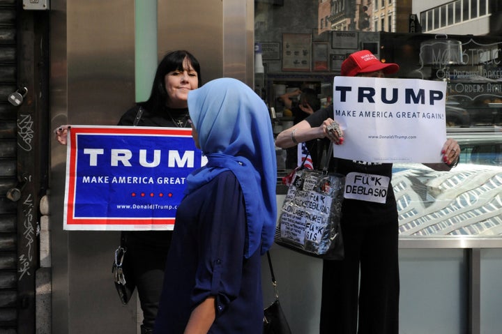 A woman walks past people holding U.S. Republican presidential nominee Donald Trump signs before the annual Muslim Day Parade in the Manhattan borough of New York City, September 25, 2016.