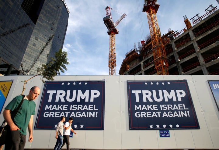 People walk past signs bearing the name of U.S. President-elect Republican Donald Trump in Tel Aviv, Israel November 14, 2016