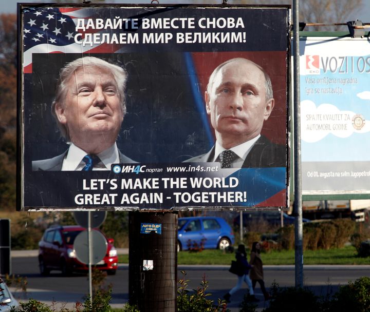 Pedestrians cross the street behind a billboard showing a pictures of US president-elect Donald Trump and Russian President Vladimir Putin in Danilovgrad, Montenegro, November 16. 2016.