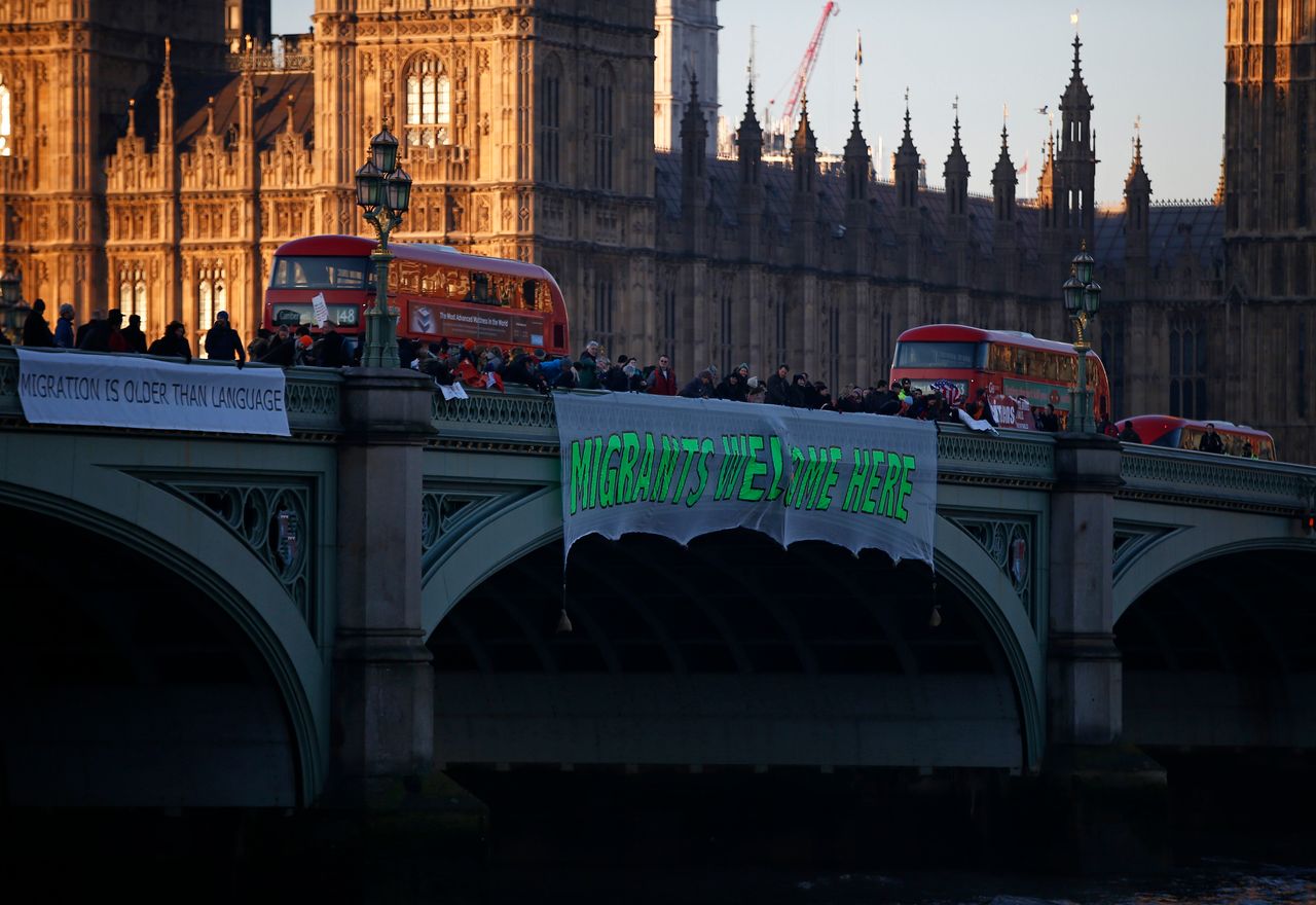 Demonstrators hang a banner that reads 'Migrants Welcome Here' from Westminster Bridge.