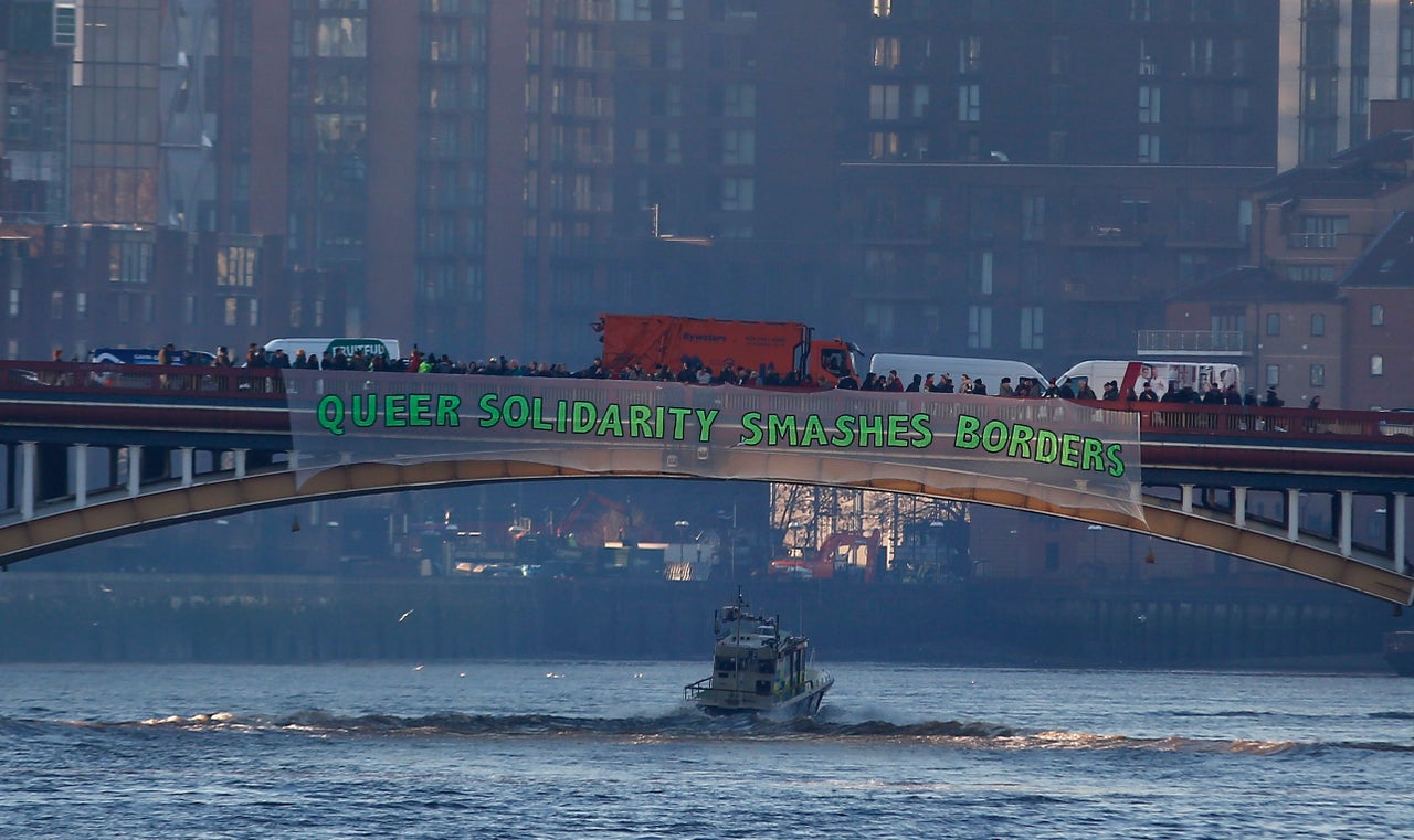 Demonstrators hang a banner that reads 'Queer Solidarity Smashes Borders'.