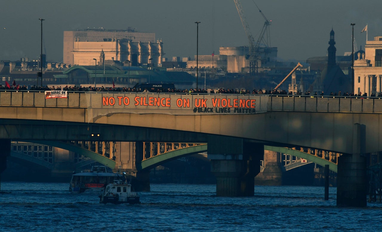 <strong>Demonstrators hang a banner that reads "No To Silence On UK Violence" from London Bridge.</strong>