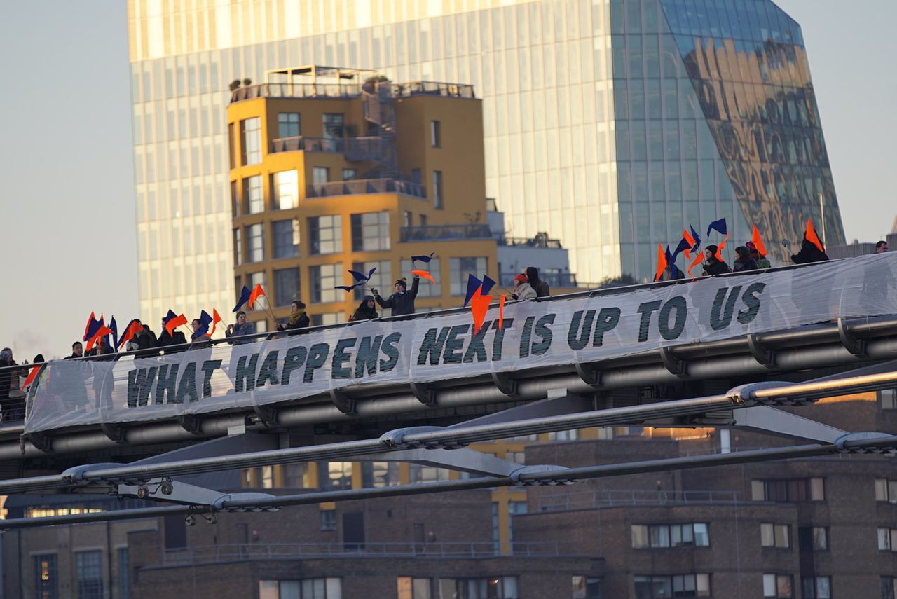 Activists drop a banner emblazoned with 'What Happens Next is Up to Us'.