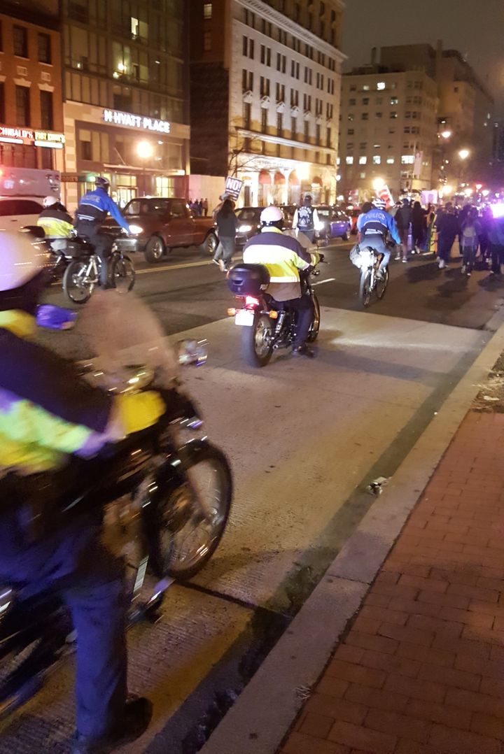 Police provide escort behind marching protesters, following a traffic blocking demonstration.
