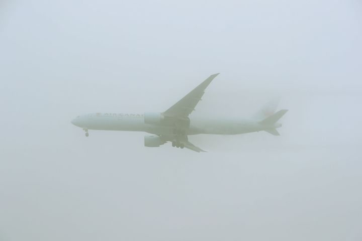 An Air Canada 777-333 comes into land through the fog at Heathrow Airport