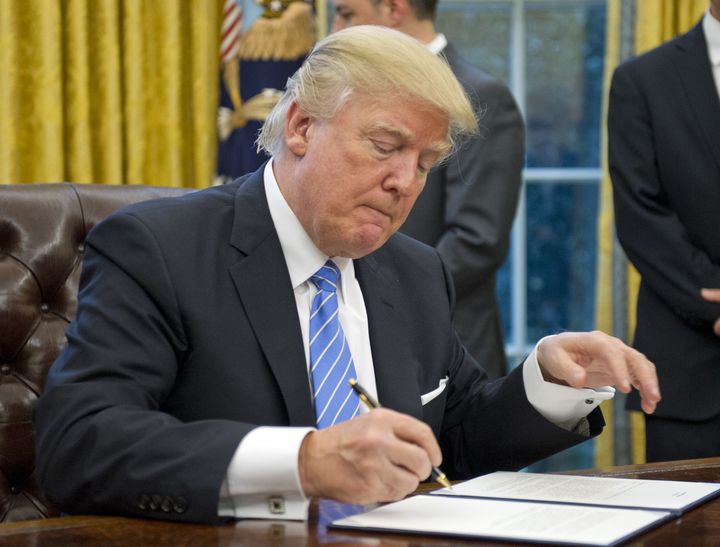 President Donald Trump signs an executive order in the Oval Office of the White House in Washington, D.C., U.S., on Monday, Jan. 23, 2017. Trump abruptly ended the decades-old U.S. tilt toward free trade by signing an executive order to withdraw from an Asia-Pacific accord that was never ratified and promising to renegotiate the North American Free Trade Agreement.