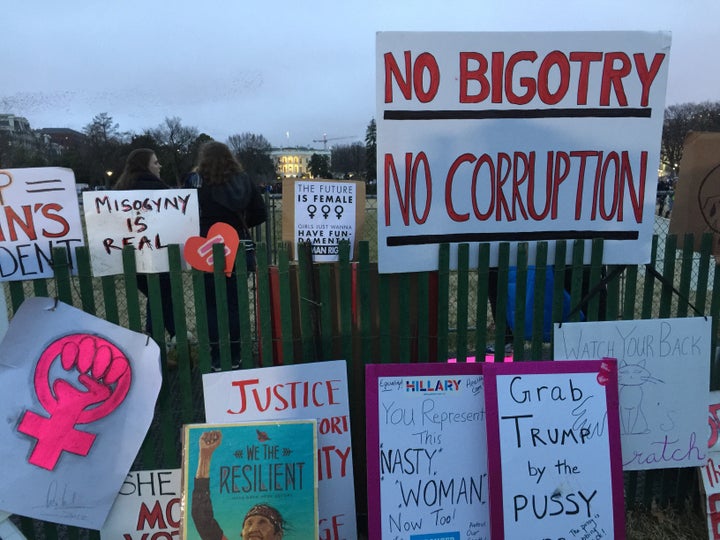 The juxtaposition of the light radiating from Trump’s White House and defiant signs of resistance.