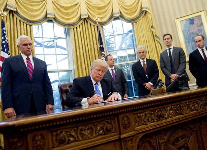 (Left) Pence looks over Trump's shoulder as he signs the executive order