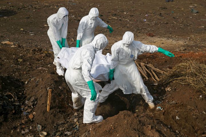 Health workers carry the body of a suspected Ebola victim for burial at a cemetery in Freetown December 21, 2014.