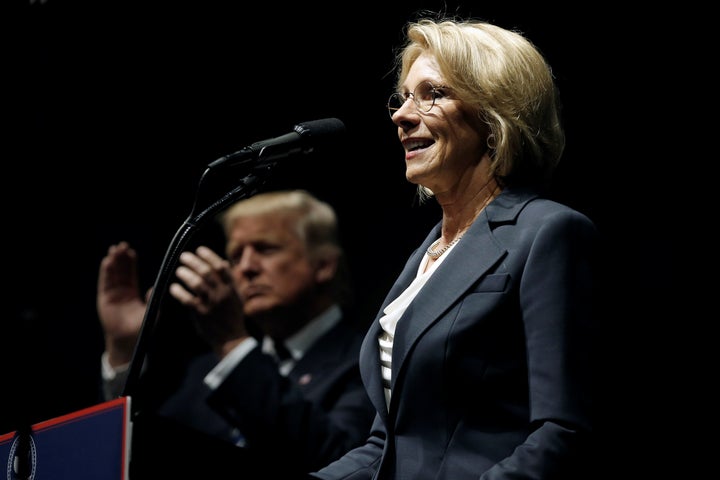 Donald Trump applauds as Betsy DeVos, his pick for education secretary, speaks at a "Thank You USA" rally in Grand Rapids, Michigan, on Dec. 9, 2016.