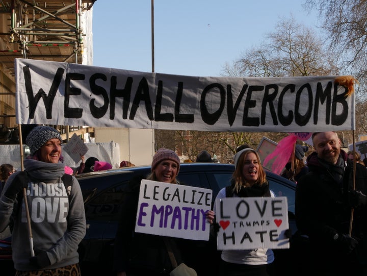 <p>Demonstrators raise a banner saying, “WE SHALL OVERCOMB,” at the Women’s March on London.</p>