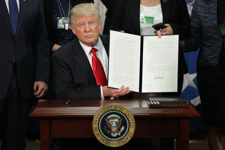 President Donald Trump holds up a signed executive order -- to build a wall on the U.S.-Mexico border -- at the Department of Homeland Security on Wednesday, Jan. 25, 2017.