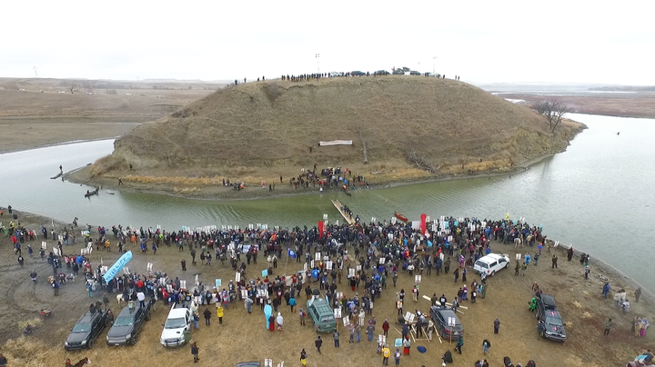 Morton County officers occupy Turtle Island, which is sacred to the Sioux Nation. Protestors gather at its base.