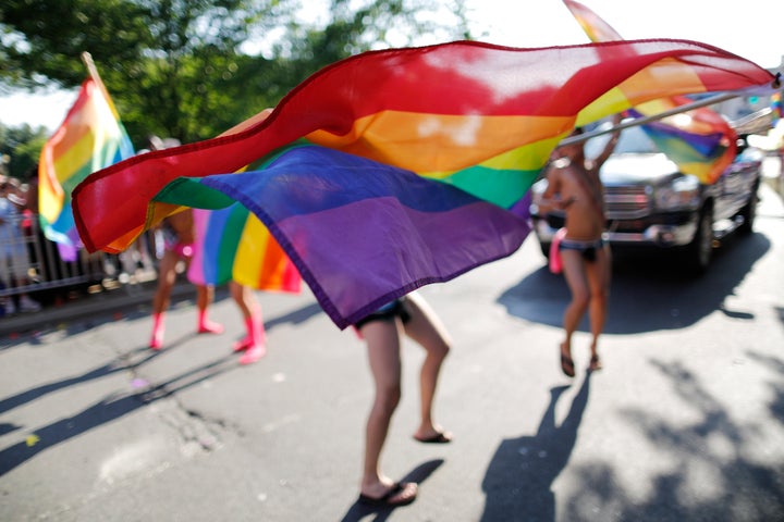 Men dance with rainbow flags as they take part in the Capital Pride Parade in Washington on June 8, 2013.