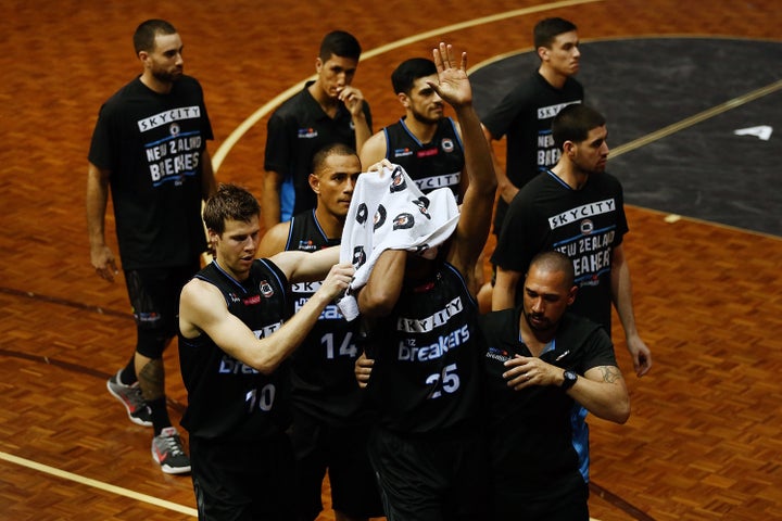 Akil Mitchell, covered by a towel, acknowledges the crowd as he is escorted off the court after a gruesome eye injury.