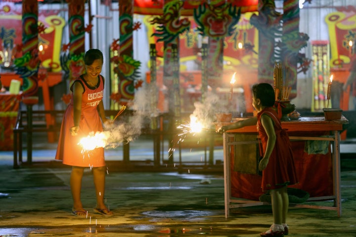 Malaysian-Chinese children play with firecrackers inside the temple ahead of Lunar New Year of the Rooster celebrations outsi