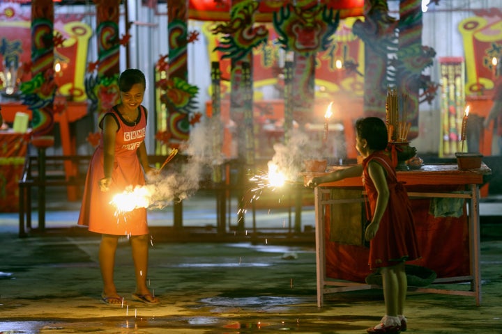 Malaysian-Chinese children play with firecrackers inside the temple ahead of Lunar New Year of the Rooster celebrations outside Kuala Lumpur on January 27, 2017 in Pulau Ketam, Malaysia.