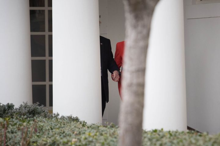 May and Trump holding hands as they walk along the White House Colonnade