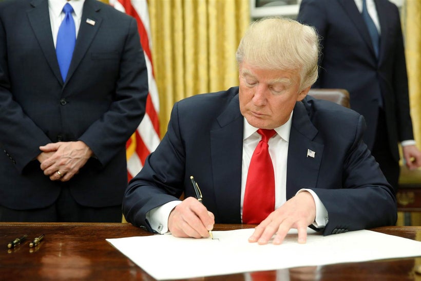 President Donald Trump signs his first executive orders in Oval Office. Read article to learn how this affected Obamacare/The