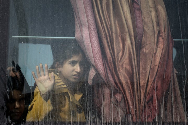 A young girl looks out a bus window for members of her family after fleeing fighting in Mosul, Iraq on Nov. 7, 2016