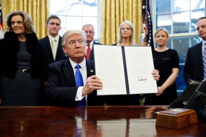 President Donald Trump holds up a signed Executive Order in the Oval Office of the White House.