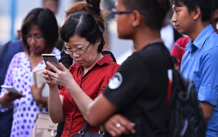 Chen Peijie (2nd L), China's consul-general in Sabah, checks her mobile phone at a jetty in Kota Kinabalu in the Malaysian Borneo state of Sabah on January 29, 2017, as she awaits developments after a tourist boat carrying 28 Chinese nationals was reported missing on January 28. (STR/AFP/Getty Images)