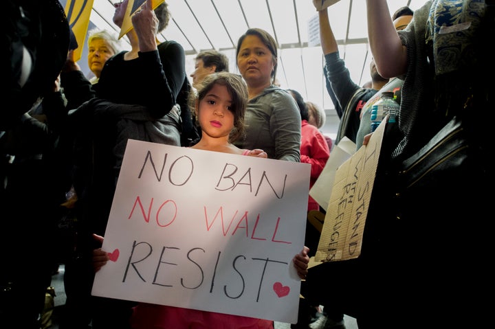 A young girl holding a sign during a protest at San Francisco airport.