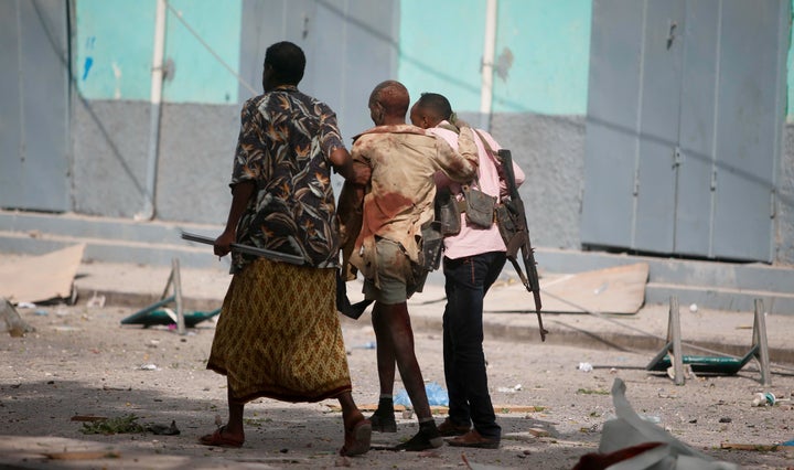 A injured government soldier is led away from the scene of an explosion in Somalia's capital, Mogadishu, on Jan. 25. Civ