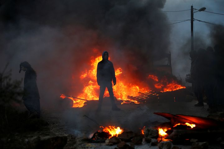Protesters stand next to fire at the entrance to the Israeli settler outpost of Amona in the occupied West Bank early morning February 1, 2017.