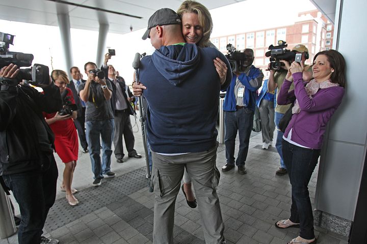 Boston Firefighter Mike Materia lifts up Roseann Sdoia to hug her after a press conference.