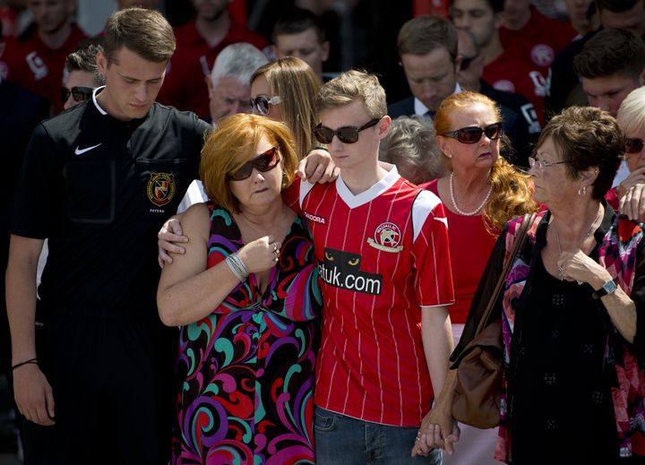Owen and his mother Suzanne observing a minute's silence at Walsall football club for his brother, uncle and grandfather 