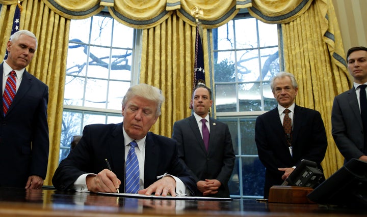 President Donald Trump signs an executive order that places a hiring freeze on non-military federal workers, Jan. 23, 2017.