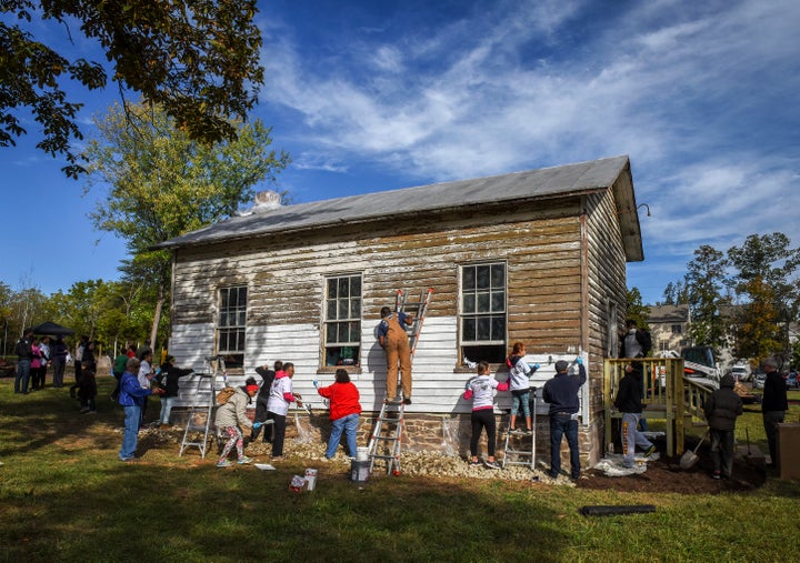 A volunteer group painting the exterior of the Ashburn Colored School, a nineteenth-century schoolhouse recently vandalized with racist symbols and hate language, on Oct. 09, 2016 in Ashburn, VA.